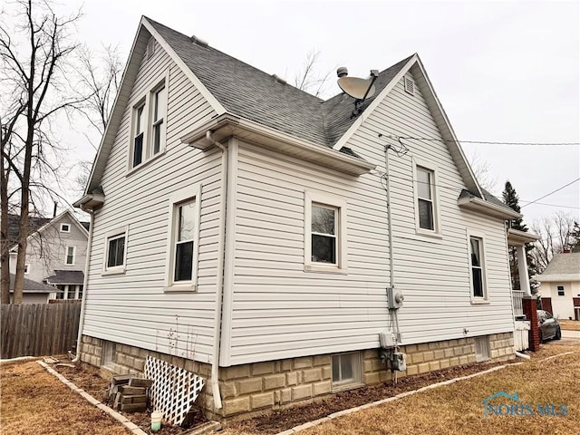 view of side of property featuring roof with shingles and fence