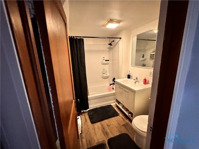 bathroom with wood finished floors, vanity, toilet, and shower / bath combo with shower curtain