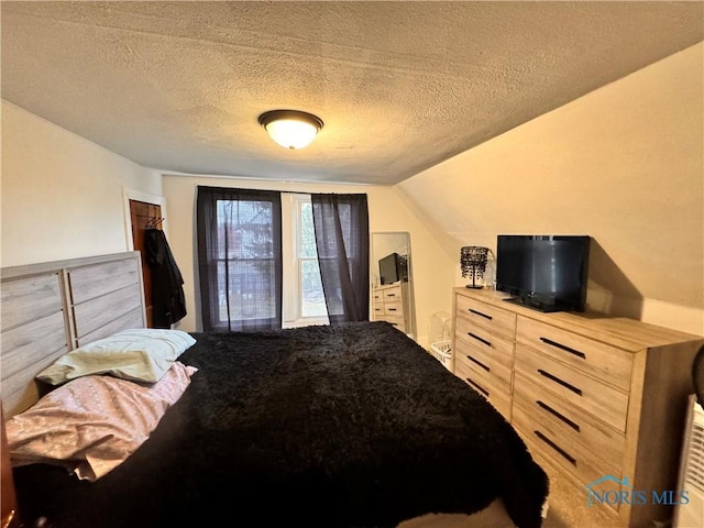 bedroom featuring vaulted ceiling and a textured ceiling