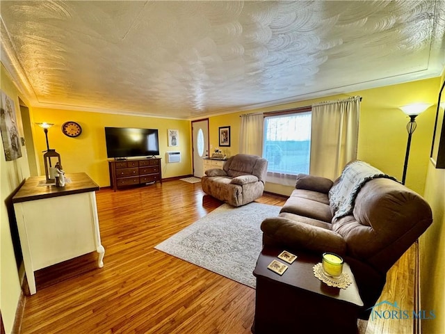 living area featuring baseboards, a textured ceiling, ornamental molding, and wood finished floors