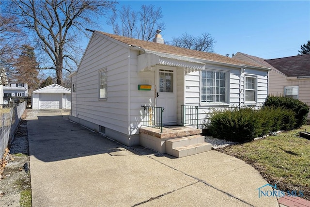 bungalow with a garage, an outbuilding, a chimney, and fence