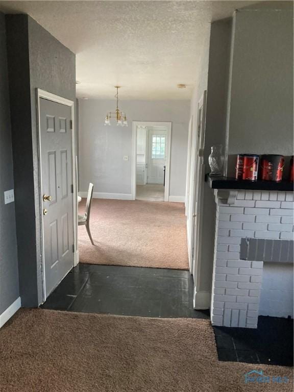 hallway featuring carpet floors, baseboards, and a textured ceiling