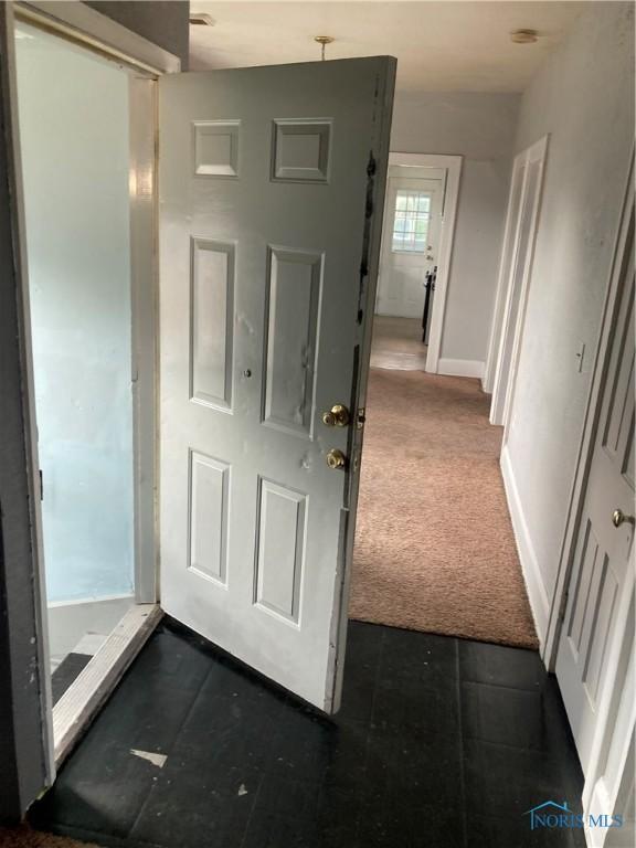 interior space featuring baseboards and dark colored carpet