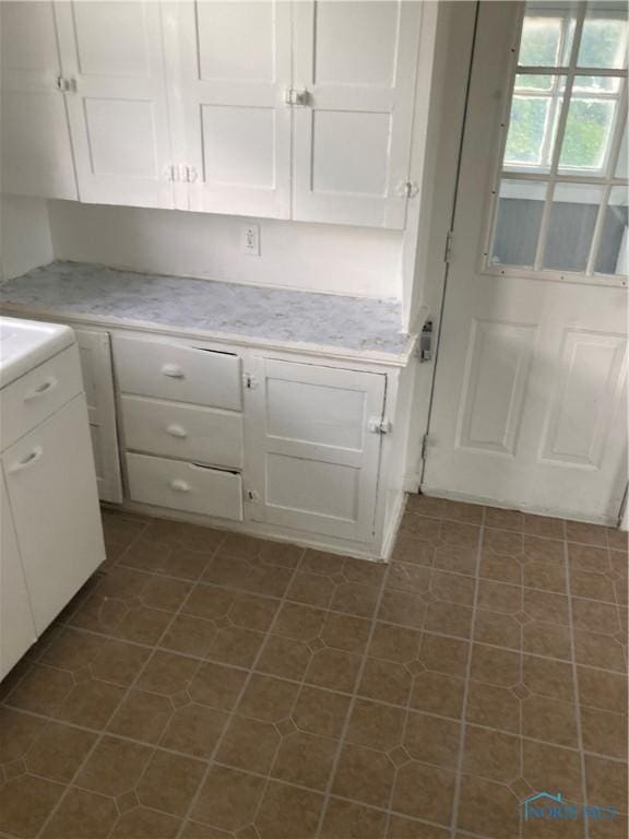 kitchen with light countertops, dark tile patterned floors, and white cabinetry