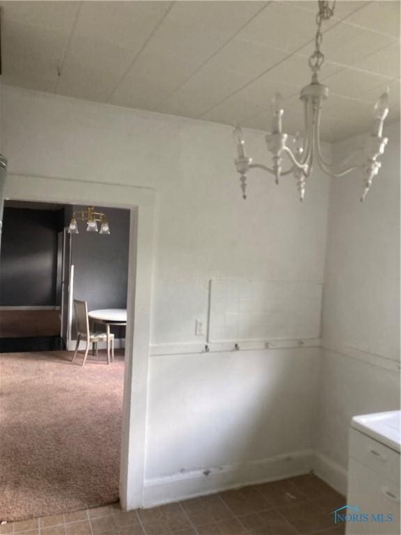 unfurnished dining area with an inviting chandelier and carpet