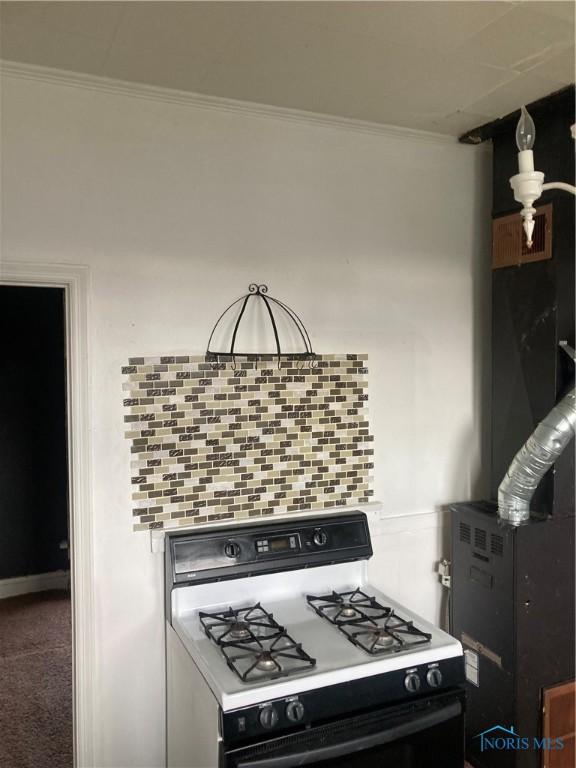 kitchen with ornamental molding, carpet, range with gas cooktop, and tasteful backsplash