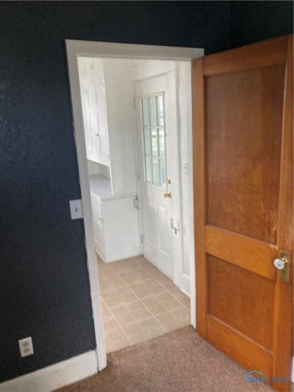 entryway with light colored carpet and light tile patterned flooring