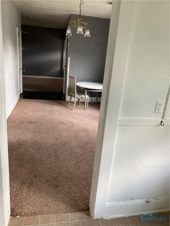 hallway with carpet, tile patterned flooring, and baseboards