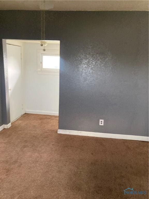 empty room featuring carpet and baseboards