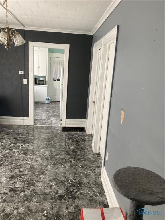 corridor with baseboards, ornamental molding, and a chandelier