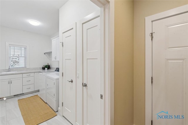 washroom with cabinet space, a sink, visible vents, and washing machine and clothes dryer