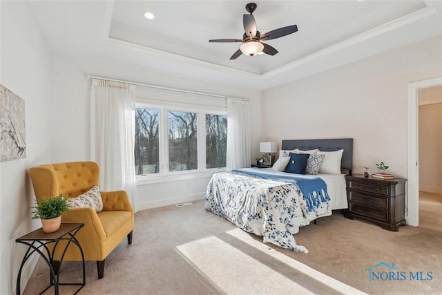 carpeted bedroom with a tray ceiling, visible vents, and baseboards