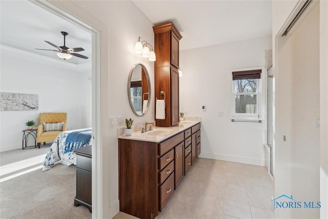 ensuite bathroom with ceiling fan, a sink, baseboards, and double vanity