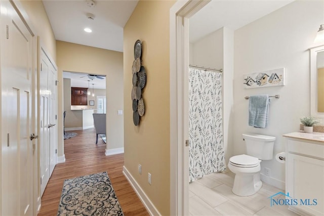 bathroom featuring baseboards, vanity, toilet, and wood finished floors