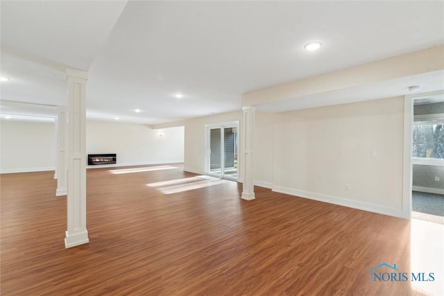 below grade area featuring a glass covered fireplace, recessed lighting, wood finished floors, and baseboards