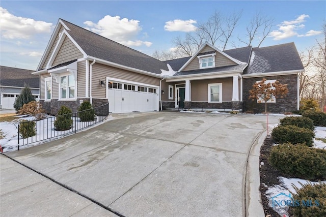 craftsman-style home with roof with shingles, concrete driveway, fence, a garage, and stone siding