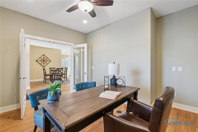 office featuring baseboards, ceiling fan, and light wood-style floors