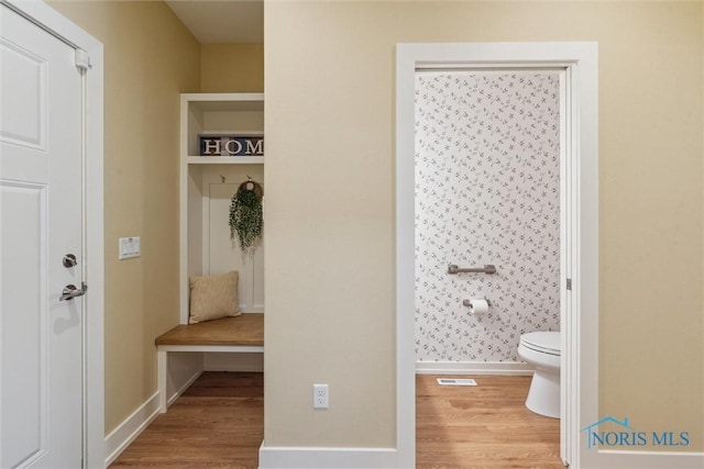 bathroom featuring toilet, wood finished floors, visible vents, and baseboards