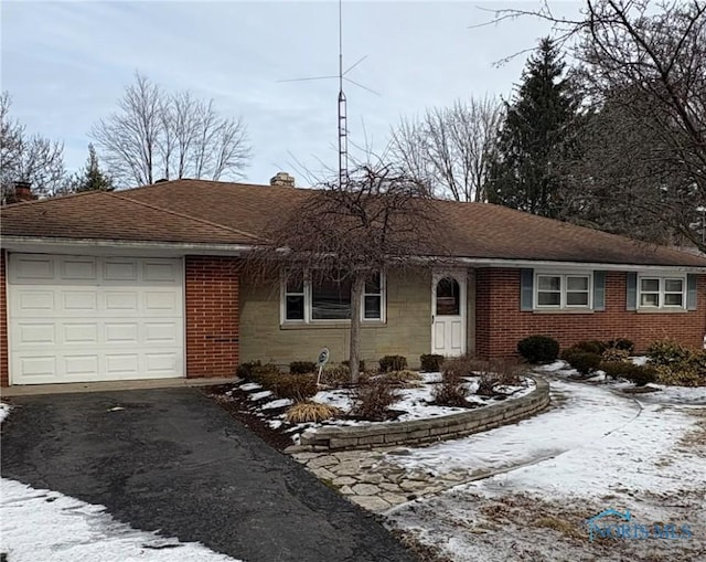 ranch-style home with aphalt driveway, a garage, a shingled roof, brick siding, and a chimney