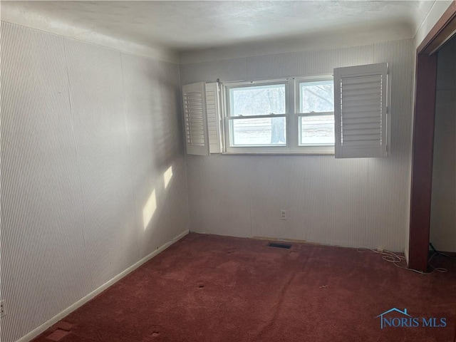 carpeted empty room featuring visible vents