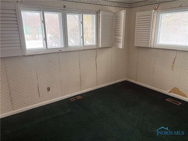 spare room featuring baseboards, dark colored carpet, visible vents, and wallpapered walls