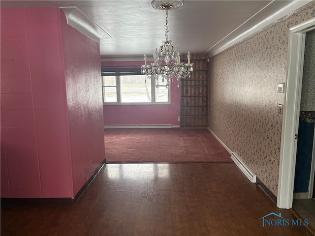 unfurnished dining area featuring wood finished floors, baseboards, an inviting chandelier, and wallpapered walls