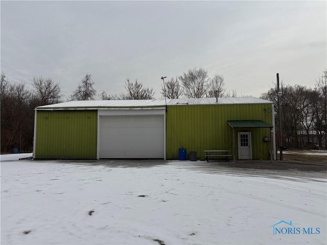 snow covered garage featuring a detached garage