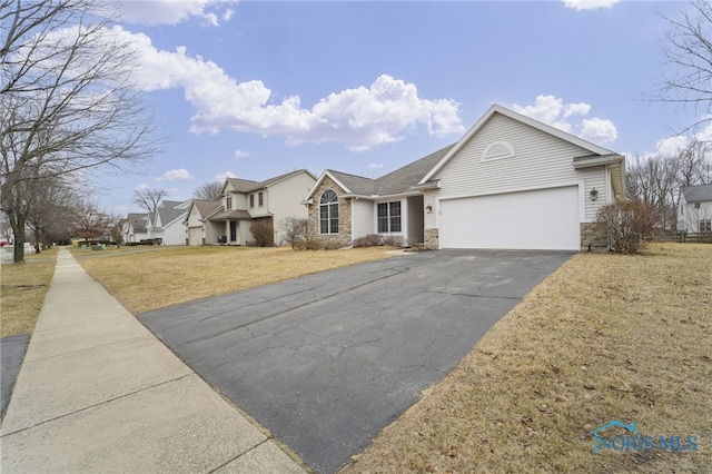 ranch-style home featuring driveway, a garage, stone siding, a residential view, and a front lawn