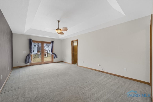 unfurnished room with light carpet, baseboards, a tray ceiling, and french doors