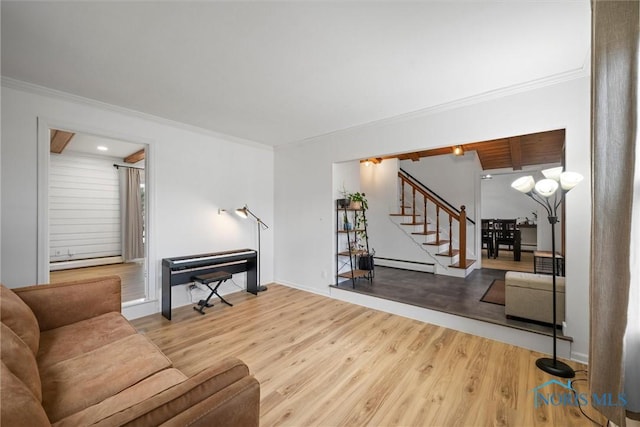 living area featuring ornamental molding, wood finished floors, baseboard heating, and stairs