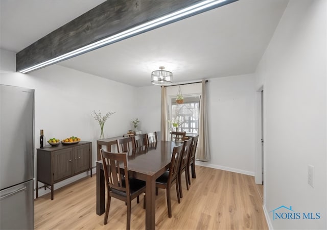 dining room with a chandelier, baseboards, beamed ceiling, and light wood finished floors