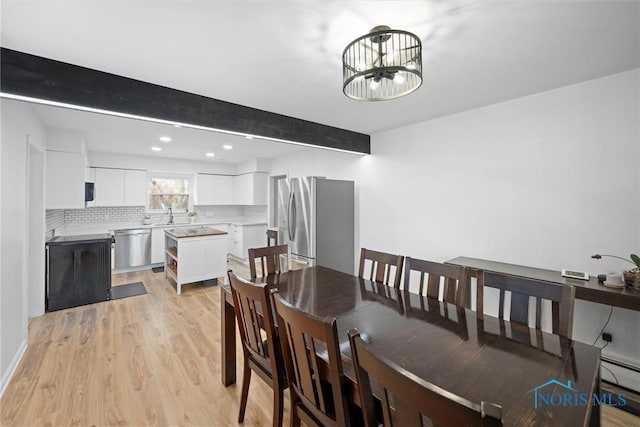 dining room with beamed ceiling, an inviting chandelier, baseboard heating, light wood-style floors, and recessed lighting