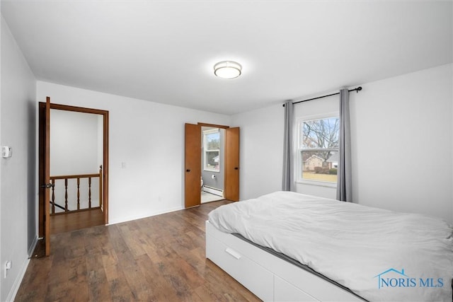 bedroom with a baseboard radiator and dark wood finished floors