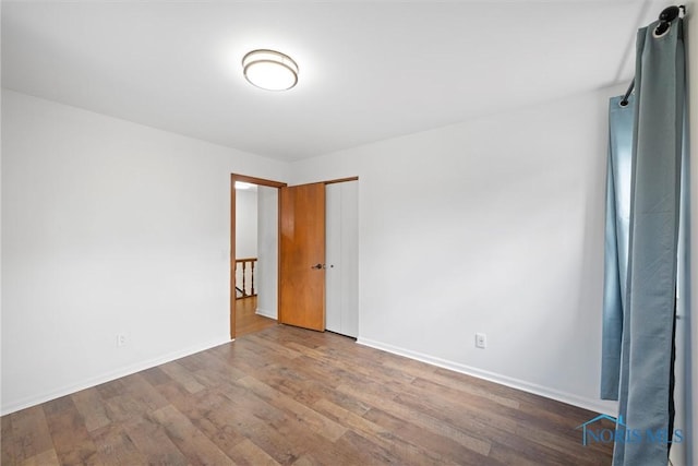 empty room featuring wood finished floors and baseboards