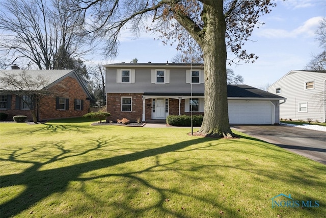 colonial house with brick siding, driveway, a front yard, and a garage