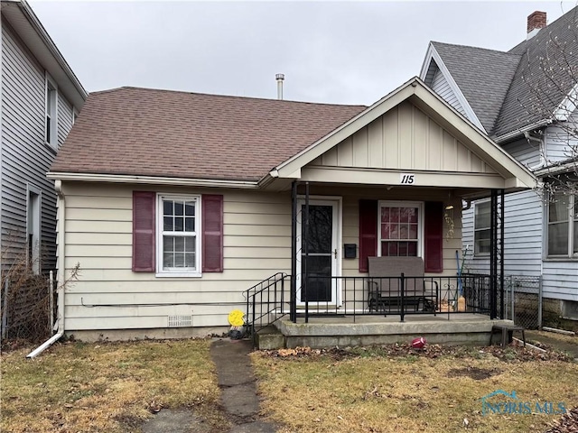 view of front of house featuring covered porch, roof with shingles, board and batten siding, and fence