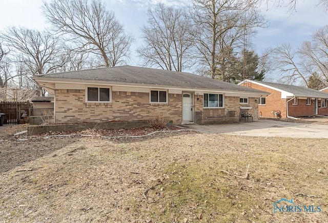 view of front facade featuring a patio, fence, and brick siding