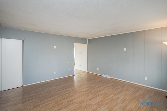 spare room with baseboards and wood finished floors