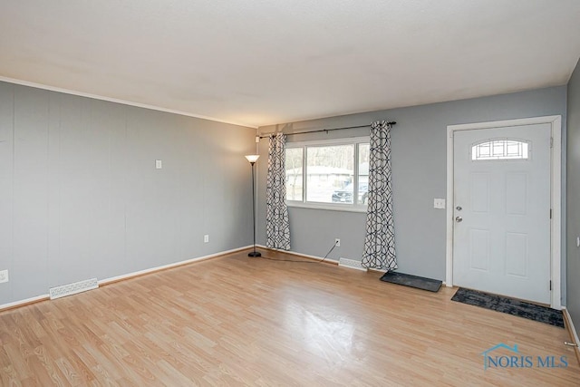 foyer entrance featuring visible vents, baseboards, and wood finished floors