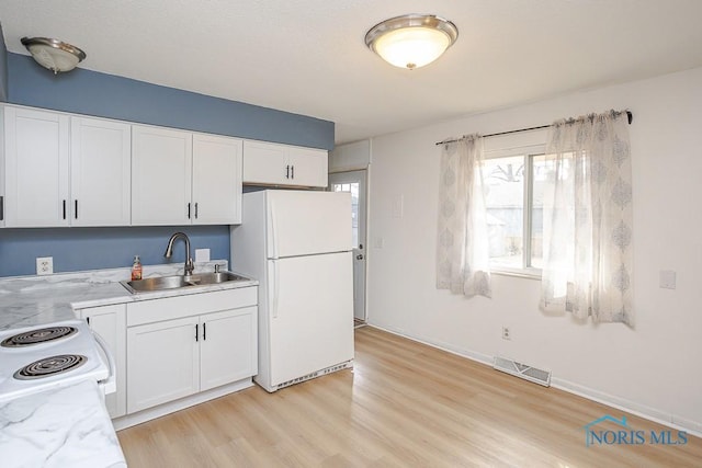 kitchen with white appliances, visible vents, light wood-style flooring, a sink, and white cabinetry