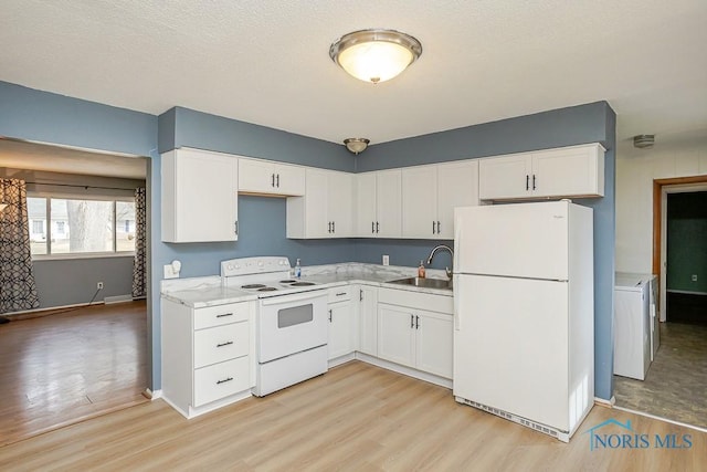 kitchen with light wood finished floors, white appliances, white cabinetry, and a sink