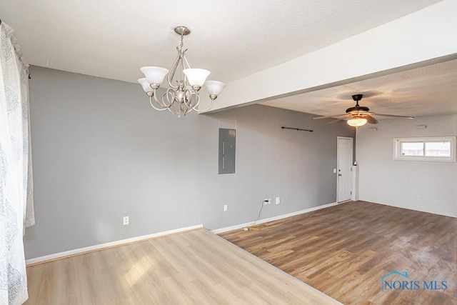 empty room featuring baseboards, electric panel, ceiling fan with notable chandelier, wood finished floors, and a textured ceiling