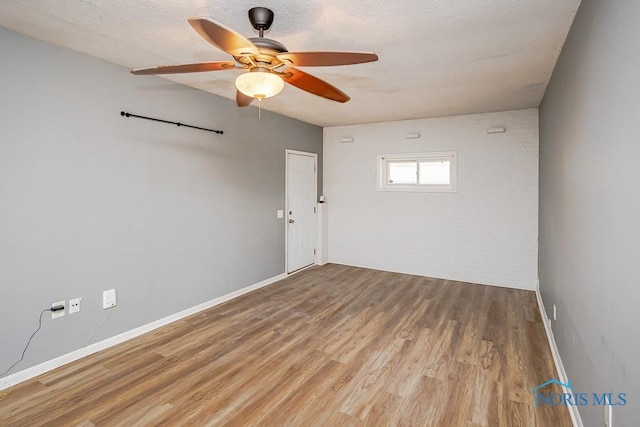 unfurnished room featuring ceiling fan, baseboards, a textured ceiling, and wood finished floors