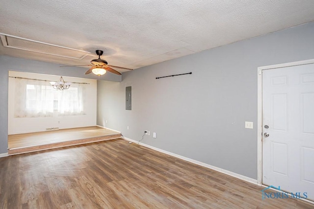 spare room featuring electric panel, baseboards, a textured ceiling, and wood finished floors