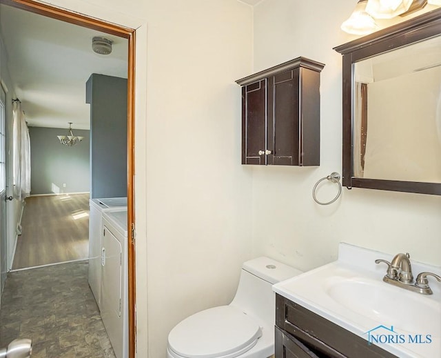 half bath with stone finish floor, toilet, vanity, and separate washer and dryer