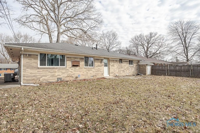 view of front of property featuring brick siding, central air condition unit, and fence