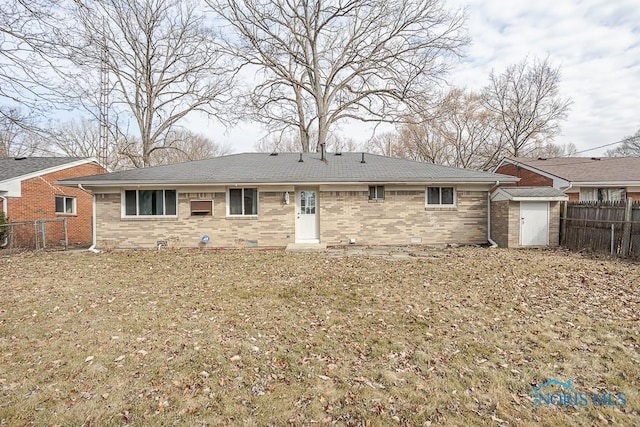 back of house with brick siding, a shed, and fence