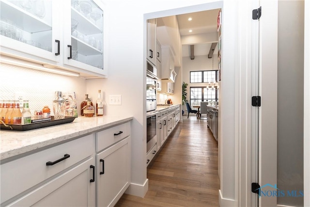 bar featuring recessed lighting, wood finished floors, beam ceiling, and decorative backsplash