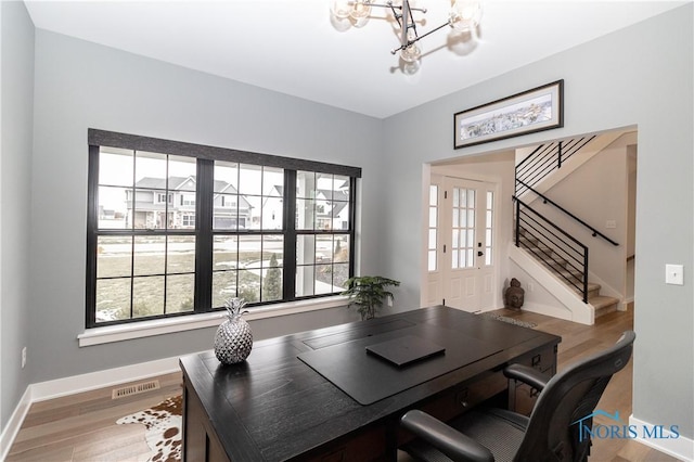 home office with an inviting chandelier, visible vents, baseboards, and wood finished floors