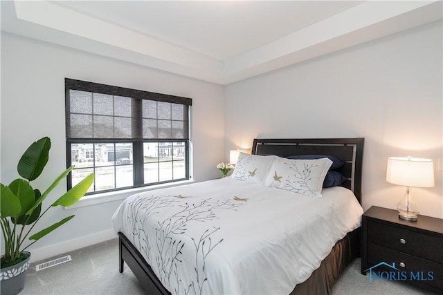 bedroom featuring carpet, a raised ceiling, visible vents, and baseboards